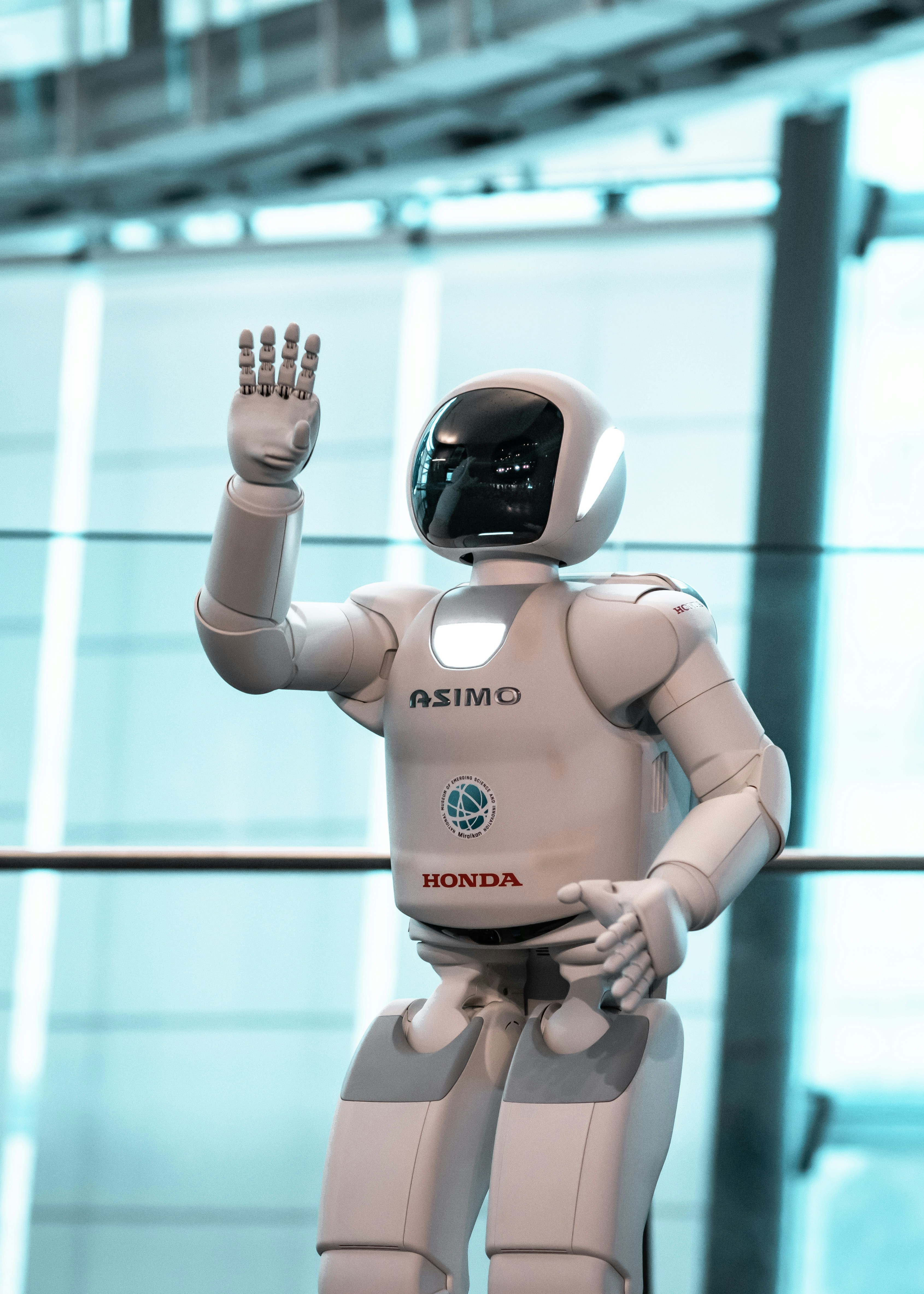 Honda ASIMO humanoider Roboter winkt vor modernem Gebäude